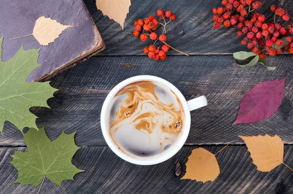 Uma xícara de café, livro velho, folhas de outono e rowan seco em madeira — Fotografia de Stock