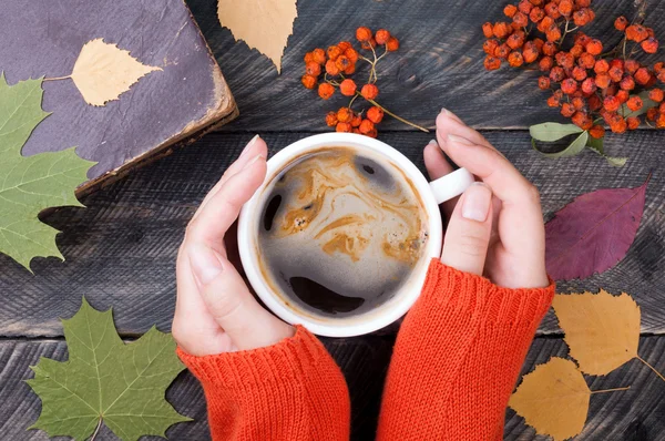Kobiece ręce trzymając kubek kawy na jesień drewniane tła. — Zdjęcie stockowe