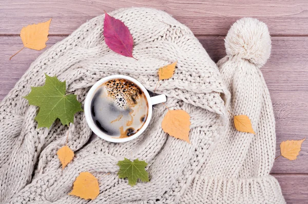 Filiżanka kawy, szalik i kapelusz ręcznie wykonane, suche liście z tyłu drewniane — Zdjęcie stockowe