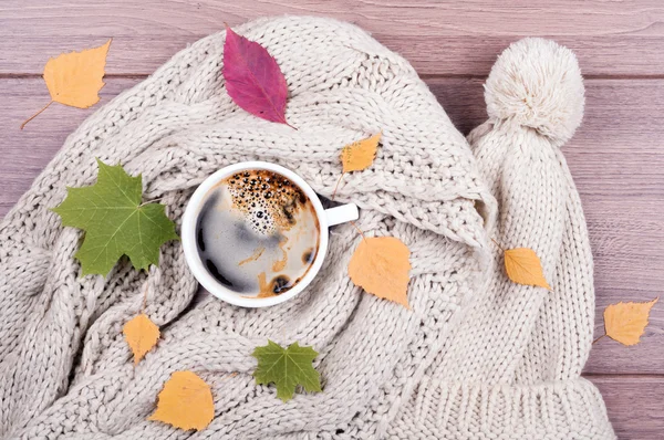 Kaffeetasse, Schal und Mütze handgemacht, trockenes Laub auf Holzrücken — Stockfoto