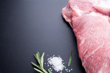 Raw meat, salt and rosemary on dark background. Lots of copy spa