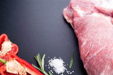 Raw meat pork with spices, herb rosemary and vegetables on a dar
