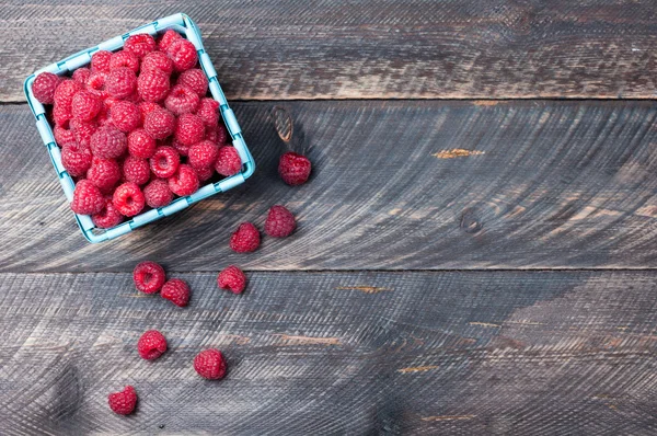 Raspberries in a basket on old wooden background. Rustic style — Stok fotoğraf