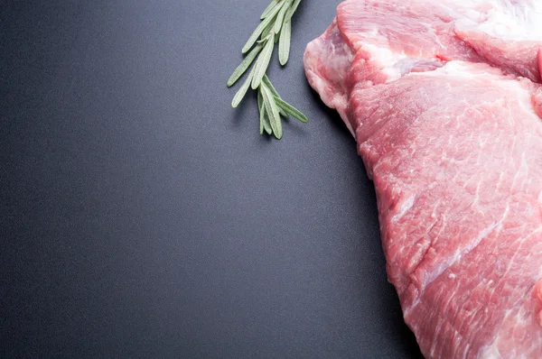 Сырое мясо и розмарин на тёмном фоне Лицензионные Стоковые Изображения