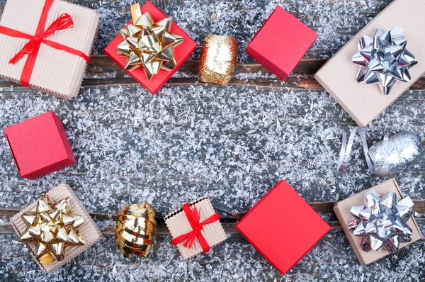 Christmas gift boxes, snow and ribbons on wooden background — Stock Photo, Image