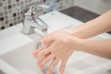Köpük sabun kullanan bir kadın ellerini yıkıyor. Hijyen konsepti el detayı.