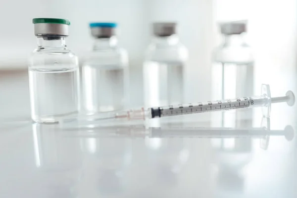 Aşı şişeleri ve şırınga beyaz masada..