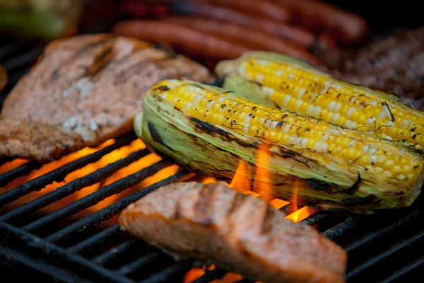 Hot dogs, steaks and salmon on a grill — Stock Photo, Image