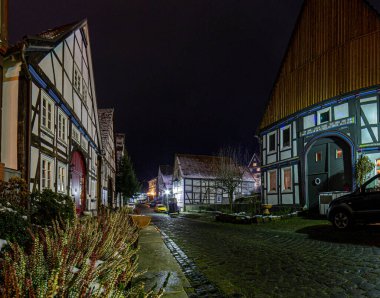 Islak havada çivili evleri ve kaldırımlı caddeleri olan eski bir Alman kasabasının gece manzarası.