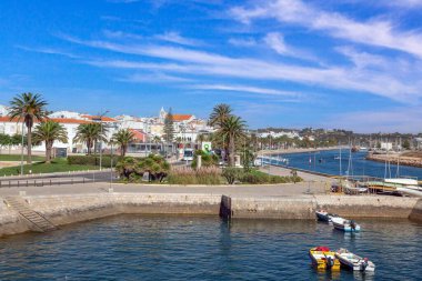 Boats calm water and palm trees along the marina and river mouth in Lagos Algarve Portugal on a clear day