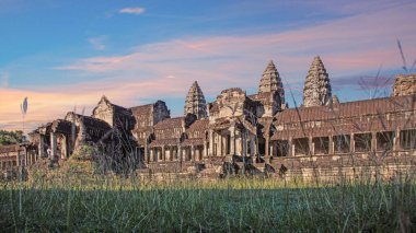 Angkor Wat temple front view in warm sunrise light in Cambodia with lush grass and no people visible
