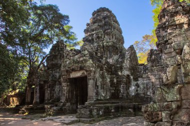 Ancient temple ruins with trees and fallen stones near Angkor Wat Cambodia no people visible