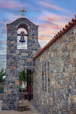 Girit 'teki tarihi taş çan kulesi ve kilise renkli akşam gökyüzü altında