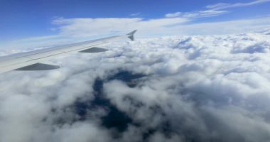 Derin mavi bir gökyüzünün altında kapalı beyaz bulut tabakasının üzerinde uçan bir yolcu uçağının hava görüntüsü. Huzurlu ve huzurlu atmosfer hava yolculuğunun güzelliğini ve doğanın enginliğini gösteriyor.