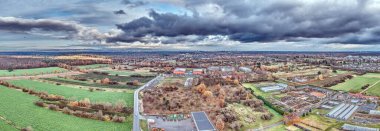 Moerfelden-Walldorf 'un geniş hava manzarası orman, tarlalar, yerleşim alanları ve bulutlu bir gökyüzünün altındaki Frankfurt ufuk çizgisini gösteriyor..