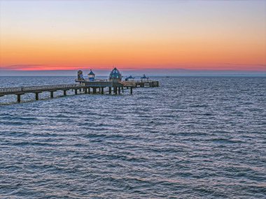 Groemitz rıhtımının Baltık Denizi 'ne uzanan uzak manzarası dramatik akşam gökyüzü altında
