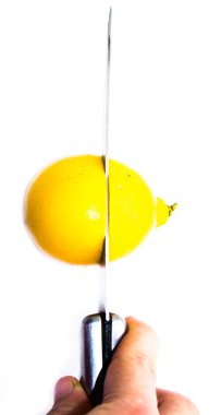 Beyaz arka planda bıçak ve limon meyveli el, yakın plan.
