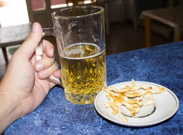 Bira bardağı elinde.