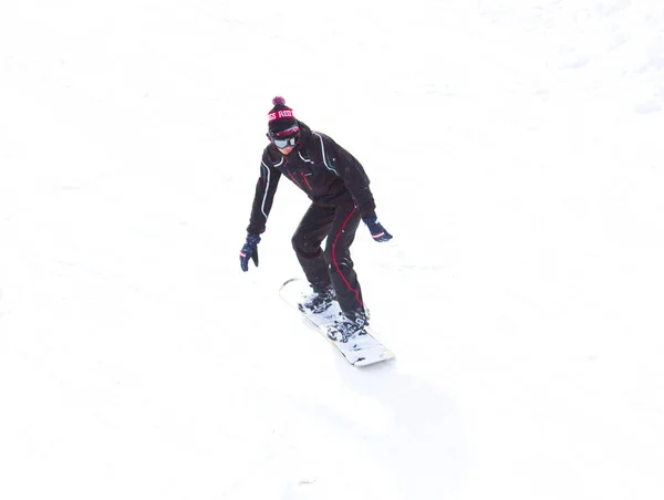 雪の中で山と一緒にスノーボードに乗っていると ジャケットの若い男がボード上の雪の上に素晴らしいスピードで動きます — ストック写真