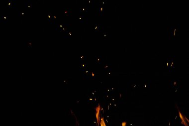 Siyah arkaplanda kıvılcımlar saçan ateş alevleri