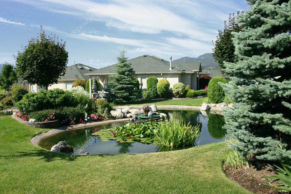 Beautiful landscaping with pond between single family homes Stock Photo