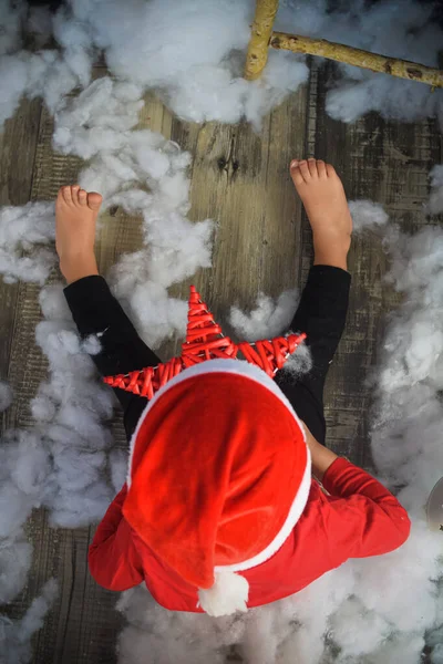 Chico bebe jüpiter disfrazado de papa noel Noel Baba claus mirando una estrella roja de navidad