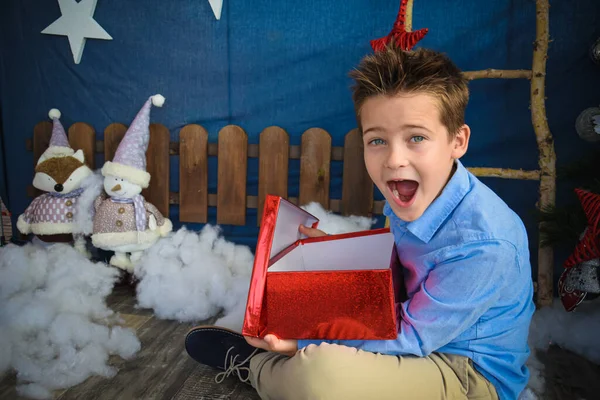 chico joven sorprendido abriendo regalo por Navidad