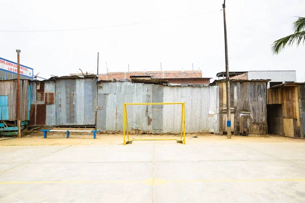 Image of sport field in shanty town. Yellow goal and concrete field.