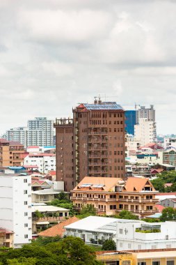 Phnom Penh şehrinin resmi. Mimaride, büyük binalarda, geleneksel evlerin yanında. İnşaat endüstrisi.