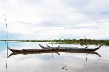 Asya 'daki balıkçı teknesiyle göl resmi. Kamboçya 'nın kırsal kesiminde geleneksel kır tekneleri