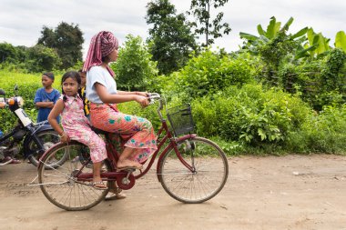 Phnom Penh, Phnom Penh / Kamboçya - 8 Ekim 2016: Khmer kırsalındaki bir kadının çocuklu bisiklet sürüşü görüntüsü. Geleneksel kıyafetler ve kırsal kesim.