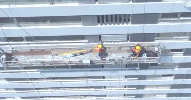 建物内の窓を掃除する労働者の空中ビデオ 航空工事建設現場での危険な仕事 ファサードの建物の窓掃除 — ストック動画