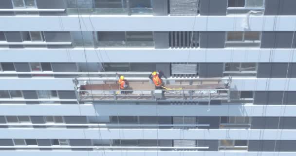 建物内の窓を掃除する労働者の空中ビデオ 航空工事建設現場での危険な仕事 ファサードの建物の窓掃除 — ストック動画
