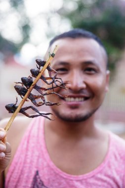 Phnom Penh, Phnom Penh - Kamboçya - 8 Kasım 2016: Kamboçya 'da kızarmış kurbağa yiyen adamın görüntüsü.