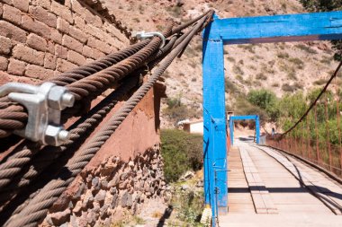 Urubamba Cusco 'daki Peru And Dağları' nda ahşaptan yapılmış bir kırsal köprü resmi. Kırsal yol Urubamba 'dan Maras' a nehri geçiyor..