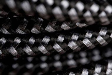 Siyah örülmüş bir kordonun ayrıntılı dokuması, dokulu yüzeyini ve iç içe geçmiş iplikleri vurgulayan yakın çekim makro çekiminde yakalanır.