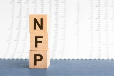 NFP - Çiftlik dışı maaş bordroları - sayıların arkaplanındaki tahta blokların dikey sırasına. NFP - Mavi arka planda tahta küplerdeki çiftliksiz maaş kısaltmaları. İş konsepti.