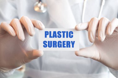 Doktor elinde plastiklerle dolu beyaz bir kart tutuyor. İki elinde de SURGERY var. Tıbbi konsept,