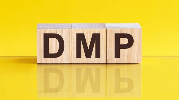 dmp word written on wood block. dmp word is made of wooden building blocks lying on the yellow table. sales, business concept, yellow background. DMP - Data Management Platform