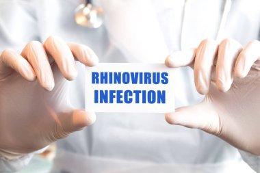 Doktor iki elinde de RHINOVIRUS istilası yazılı bir kart tutuyor. Tıbbi konsept,