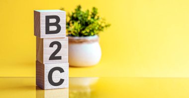 Motivasyon Sözcükleri: 3d tahta alfabe harfli B2C, kopyalama alanı olan parlak sarı bir zemin üzerinde. İşletmeden tüketiciye, kavram