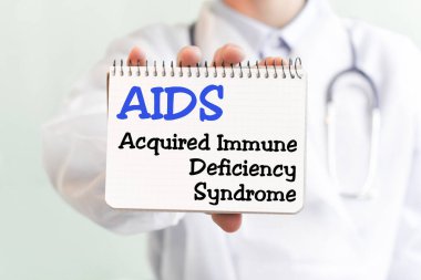 Doktor AIDS 'li bir kart tutuyor. Edinilmiş bağışıklık yetmezliği sendromu. Tıbbi konsept. Metin tıbbi bir dergide mavi harflerle yazılmış.