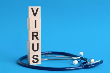Virüs kelimesi tahta bloklara ve steteskop üzerine yazılmış açık mavi arka plan, sigorta ve tıbbi konsept
