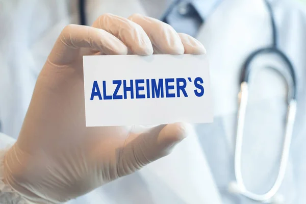 Doctor holding a white paper card with text ALZHEIMERS, medical concept. ALZHEIMERS card in hands of medical doctor