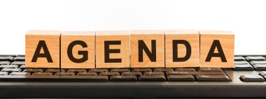 Yapı taşlarıyla yapılmış gündem kelimesi. Siyah yazı tipiyle yazılmış bir sıra tahta küp siyah bir klavyede yer almaktadır..