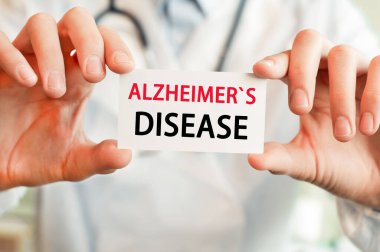 Doktor her iki elinde de ALZHEIMERS hastalığı yazılı bir kart tutuyor. Tıbbi konsept. Hastane, klinik ve tıbbi otobüsler için sağlık hizmetleri kavramı.