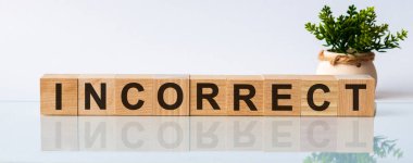 Tahta blokta yanlış sözcük. Ahşap blok iş kavramı beyaz arka plan üzerinde yanlış motivasyon metni. Ön görüş kavramları, arka planda çiçekler.