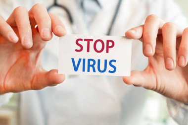 Doktor elinde VİRUS tıbbi konsepti olan bir kart tutuyor.