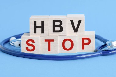 Üzerinde HBV Stop yazan tahta blok. Masada steteskop, sigorta ve tıbbi konsept mavi arka plan, sağlık sigortası ve tıbbi konsept var. HBV - Hepatit B Virüsü