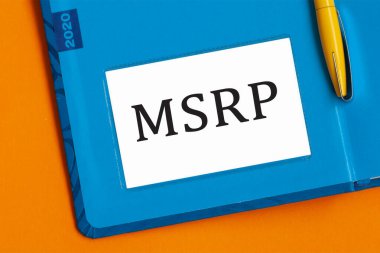 MSRP kelimesi beyaz not kağıdına siyah harflerle yazılmıştır. Mavi günlüğün arka planında sarı bir kalem gömülü. MSRP - üreticinin önerisi perakende fiyatı
